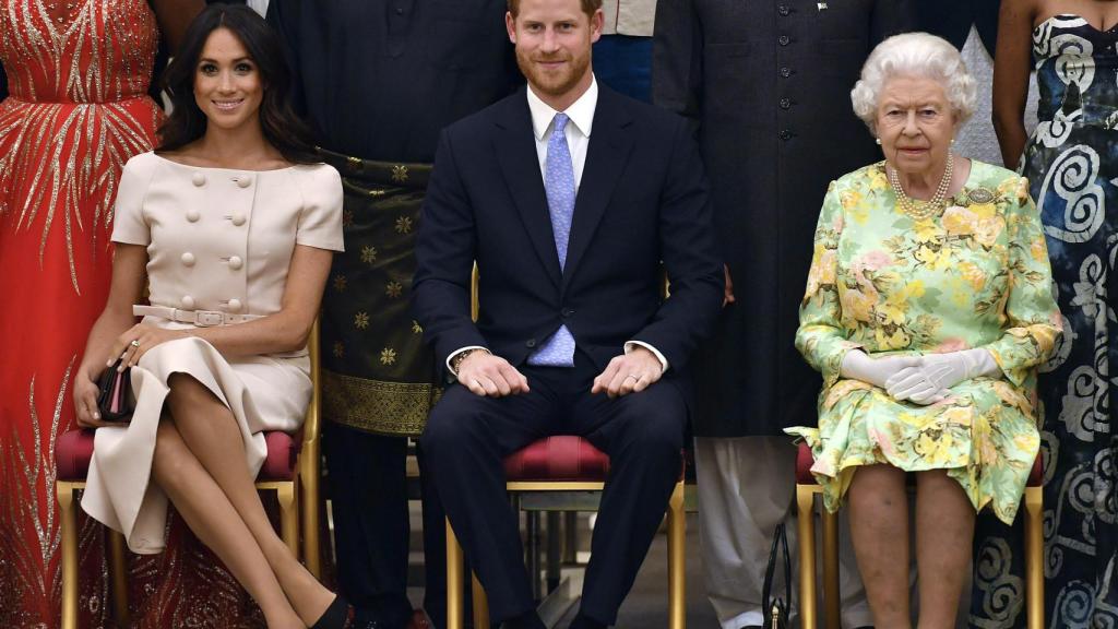 Meghan Markle y el príncipe Harry, junto a la reina Isabel, en la entrega de unos premios, en 2018.