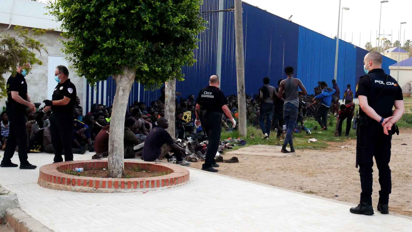 Agentes de la Policía Nacional, junto a un grupo de inmigrantes este jueves, en Melilla.