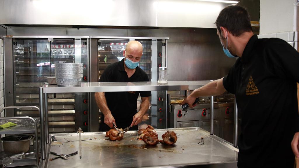 Dos trabajadores de Casa Galván, despachando los pollos asados recién hechos.