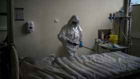 Una trabajadora de la limpieza desinfecta una cama hospitalaria.