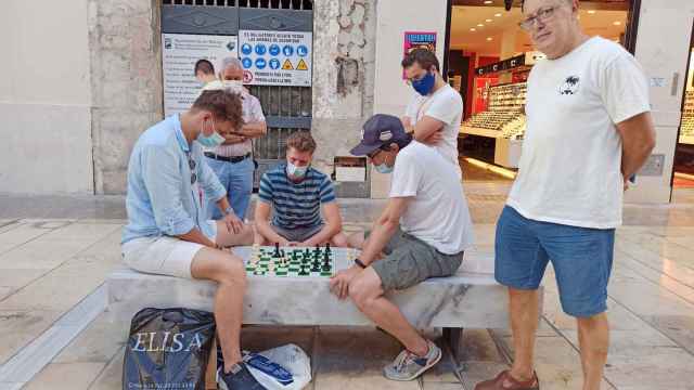 José Antonio orgulloso posando junto a unos desconocidos que juegan al ajedrez.