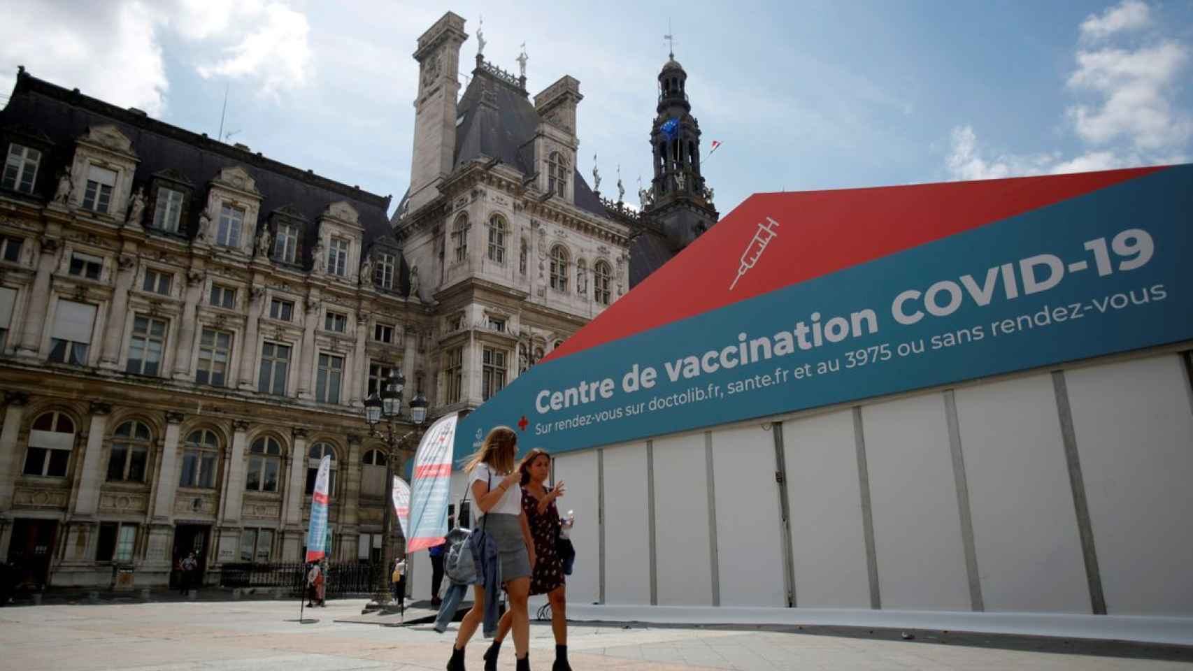 Dos mujeres caminan delante de un centro de vacunación en París.