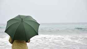 Una mujer con paraguas en la playa.