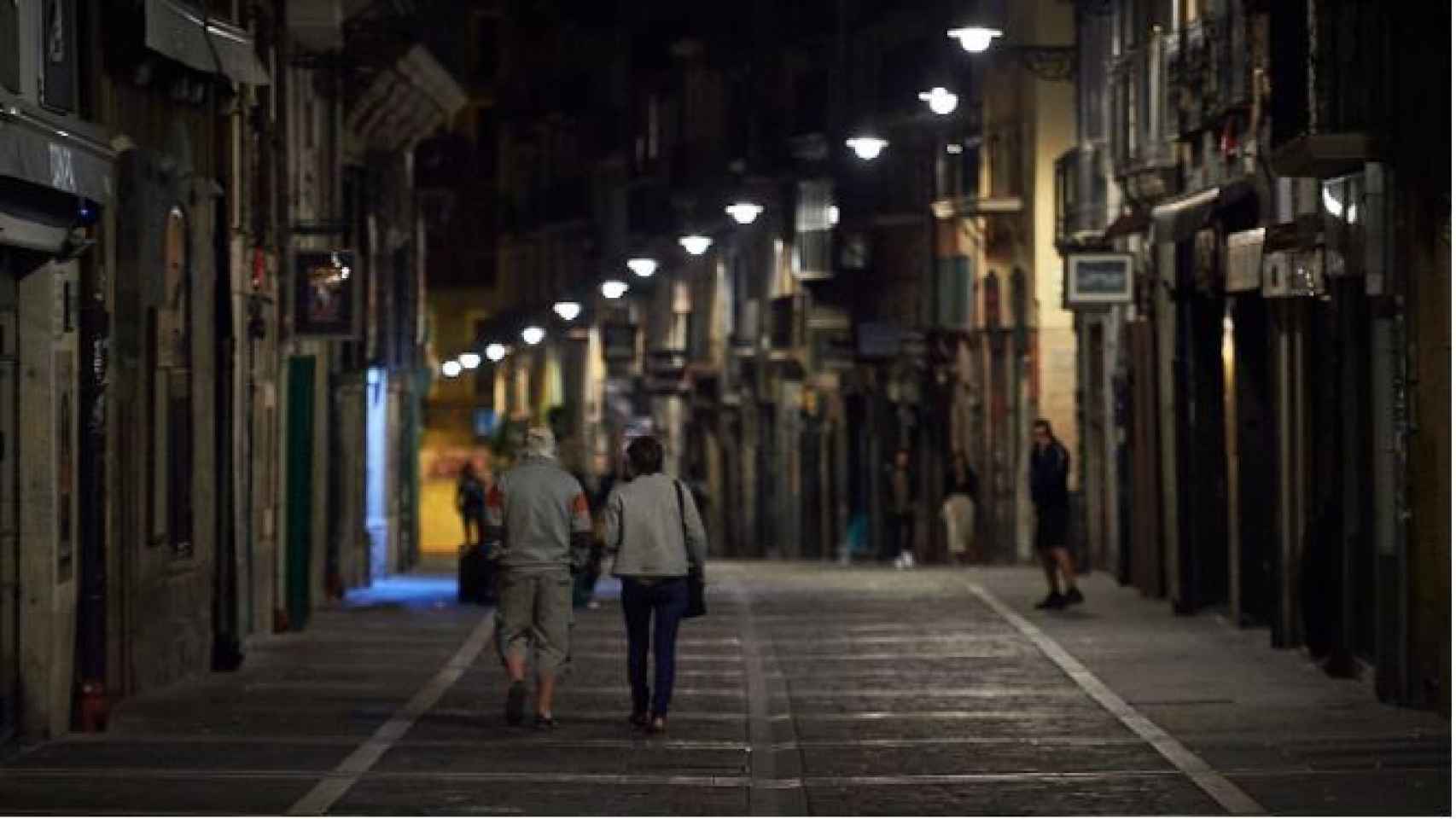 Varias personas caminan por una calle de Pamplona minutos antes del toque de queda.