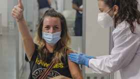 Una joven sonríe y saluda mientras recibe la vacuna contra la Covid-19 en Valencia. Rober Solsona / EP.