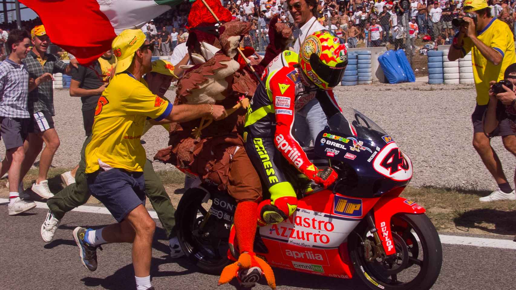 Valentino Rossi celebra su victoria en el Gran Premio de Cataluña de 1999 con un pollo subido a su moto.
