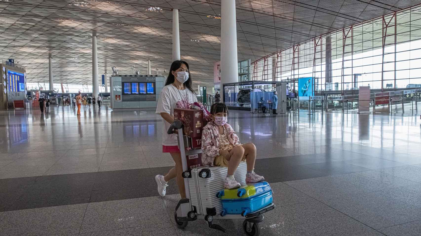 Una mujer empuja un carrito del aeropuerto en el aeropuerto de Pekín.