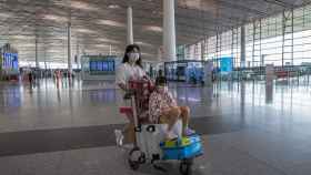 Una mujer empuja un carrito del aeropuerto en el aeropuerto de Pekín.