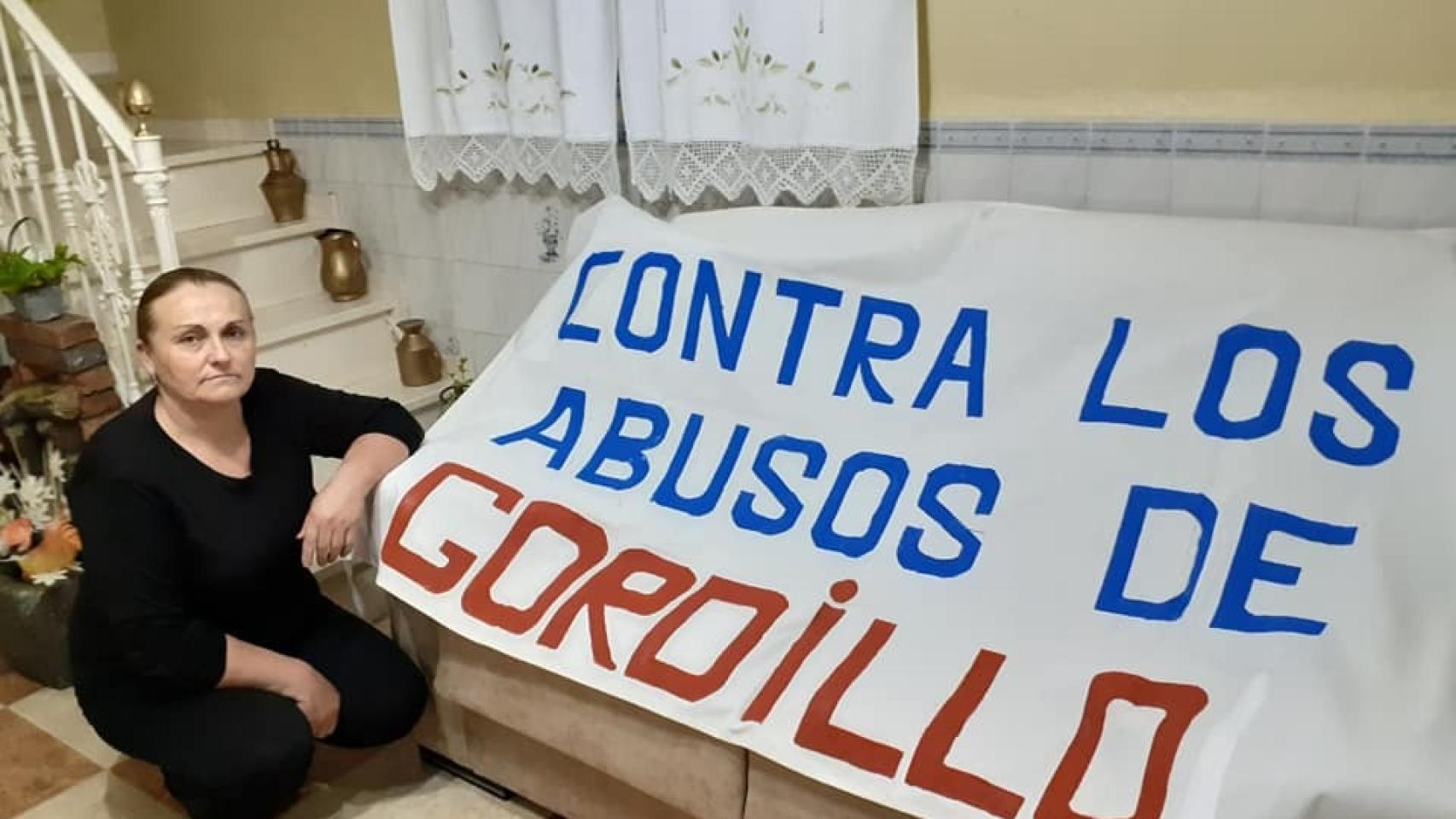 Margarita posa en su casa con su pancarta contra Sánchez Gordillo.