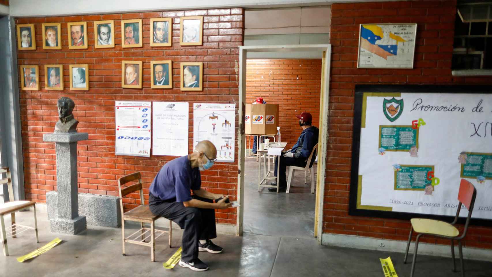 Un hombre espera para votar junto a un busto de Simón Bolivar en un centro de votación de las primarias del PSUV.