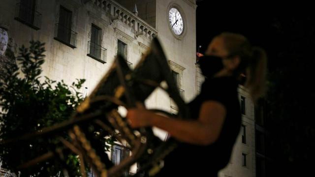 Una empleada de un restaurante recoge las sillas del local ante el toque de queda.
