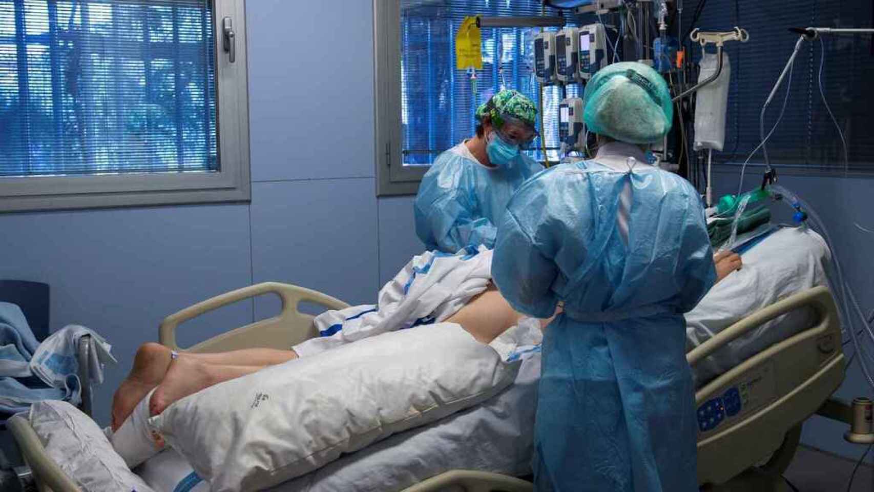 Dos sanitarios atienden a un paciente en la UCI de un hospital.