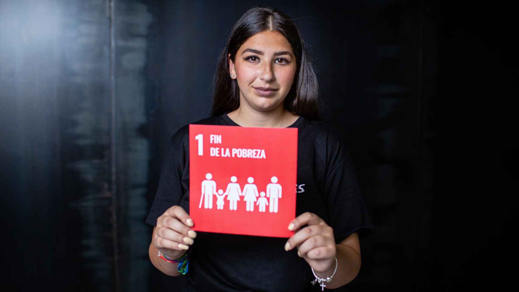 Victoria Santiago sostiene el cartel del ODS 1 (fin de la pobreza) sobre el que trabaja.