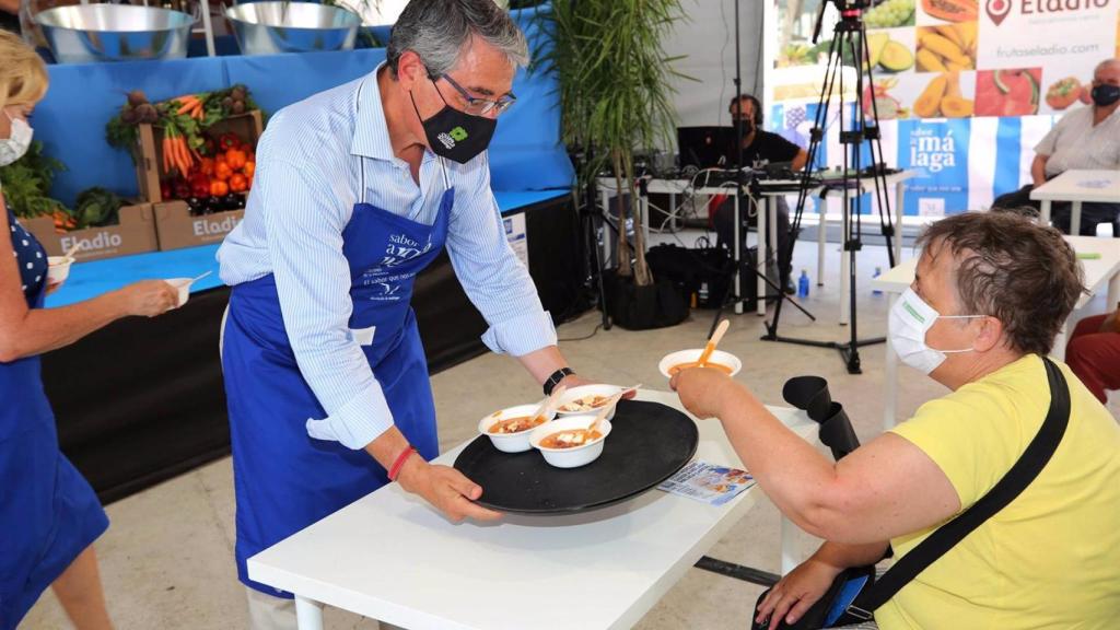 El presidente de la Diputación de Málaga reparte raciones de porra entre los asistentes a la feria.