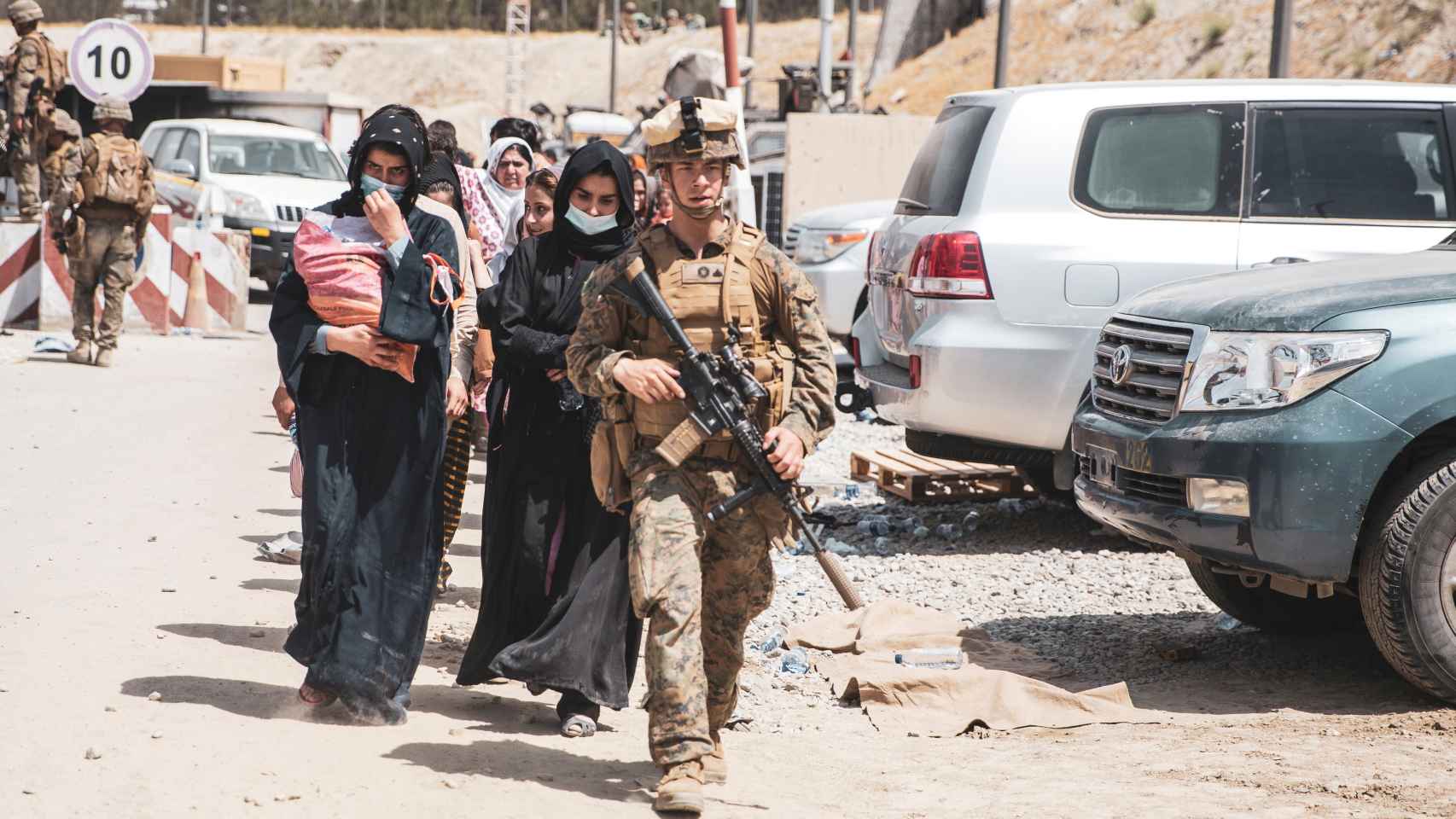 Un militar custodiando a un grupo de afganos para ser evacuados.
