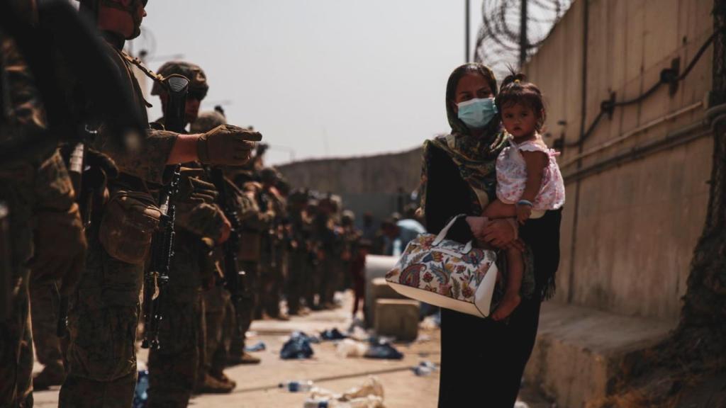 Una mujer, en la entrada del aeropuerto de Kabul, con una niña en brazos.