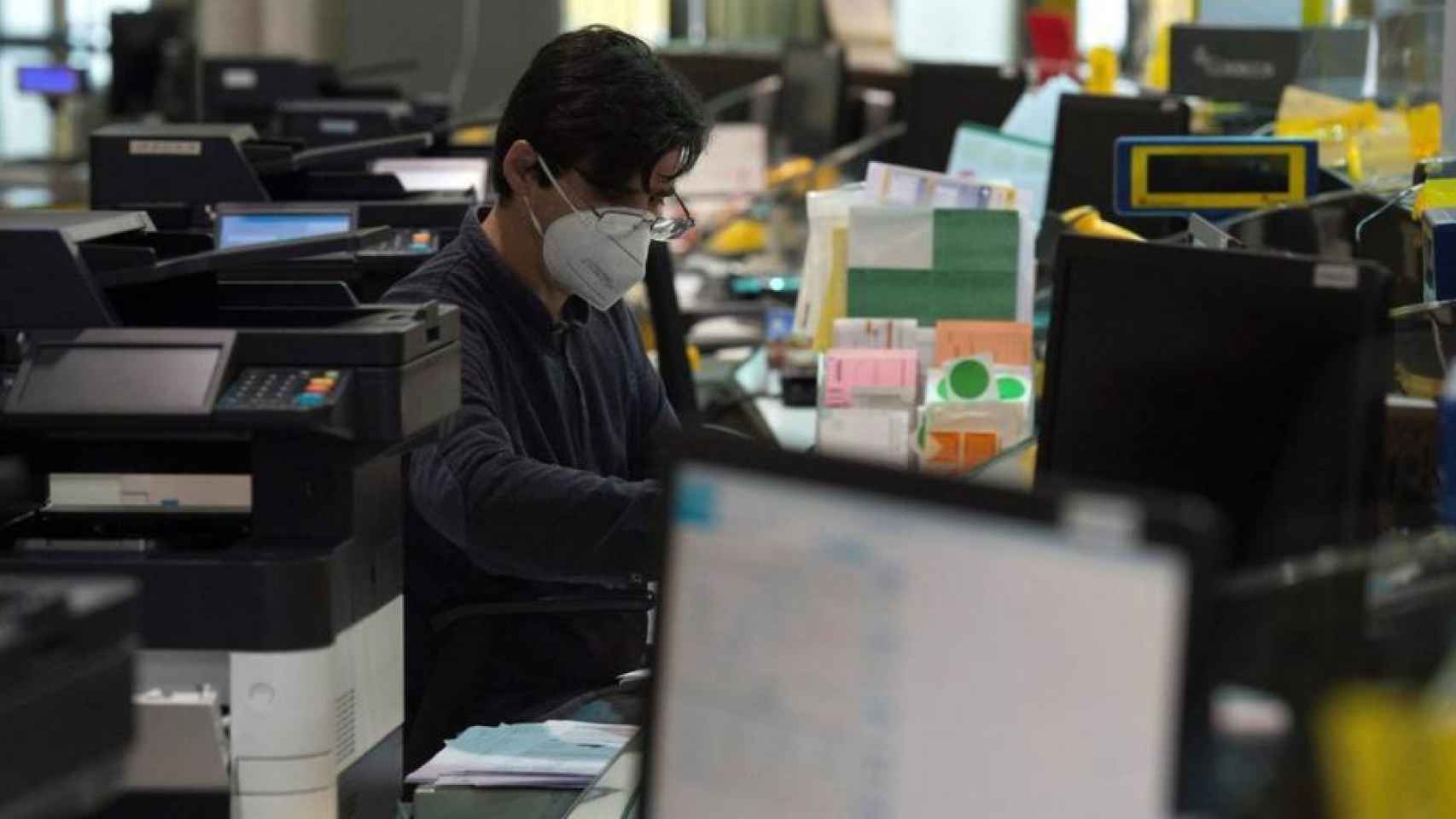 Un trabajador llevando mascarilla en una oficina.