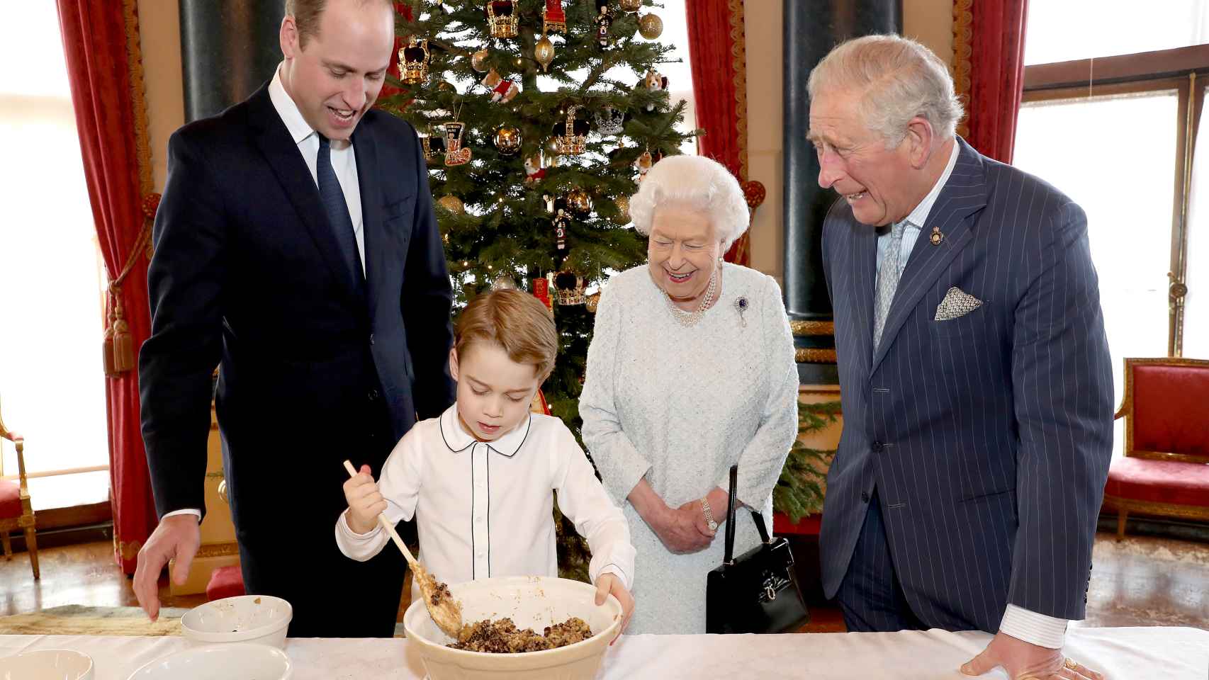 El príncipe George preparando una receta navideña con el príncipe Guillermo, el príncipe Carlos y la reina Isabel II.