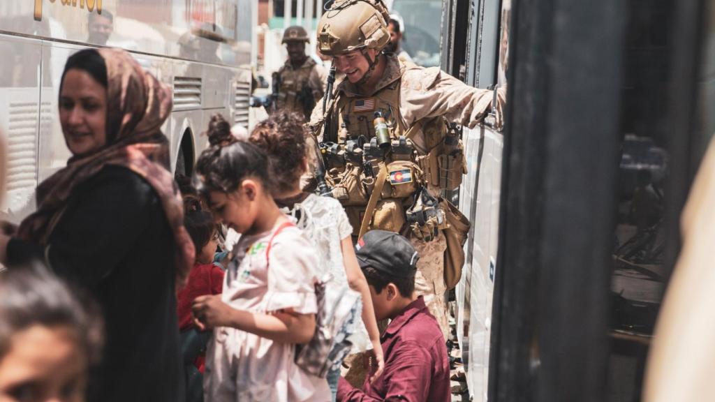 Un soldado estadounidense habla con un grupo de niños, en el aeropuerto de Kabul.