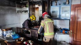 Bomberos apagando el fuego que se originó en la cocina de la vivienda.