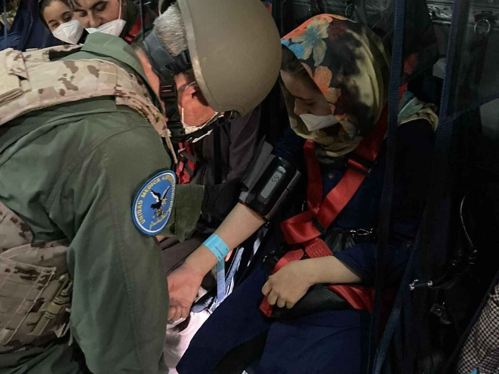 Los sanitarios militares atienden a una mujer afgana en un vuelo de evacuación.