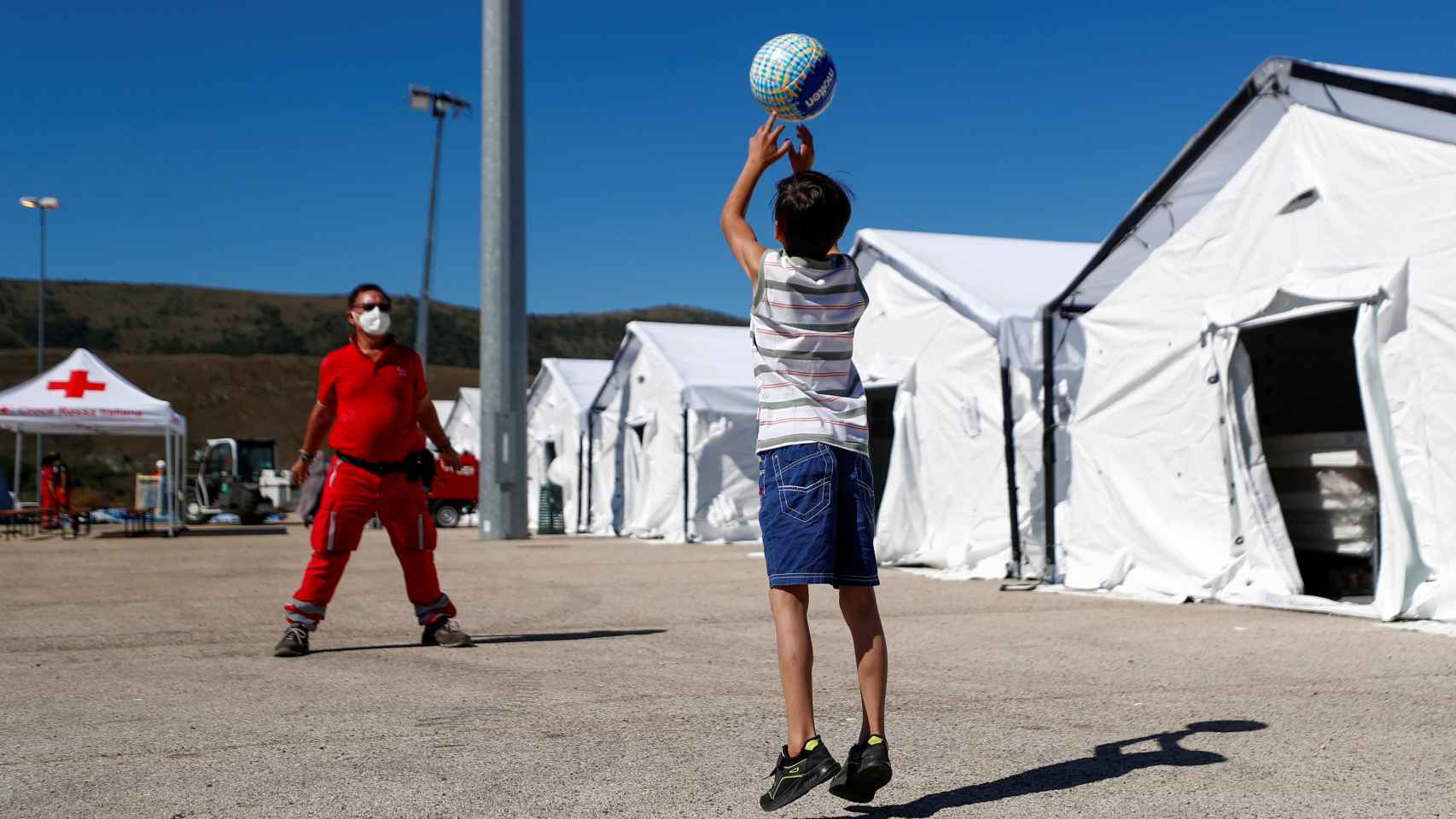 Unos niños afganos juegan a la pelota en el campamento de Cruz Roja en Avezzano (Italia).