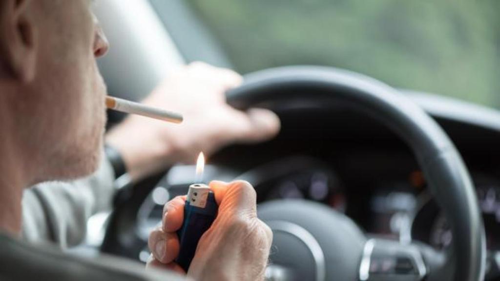 Conductor encendiendo un cigarrillo al volante