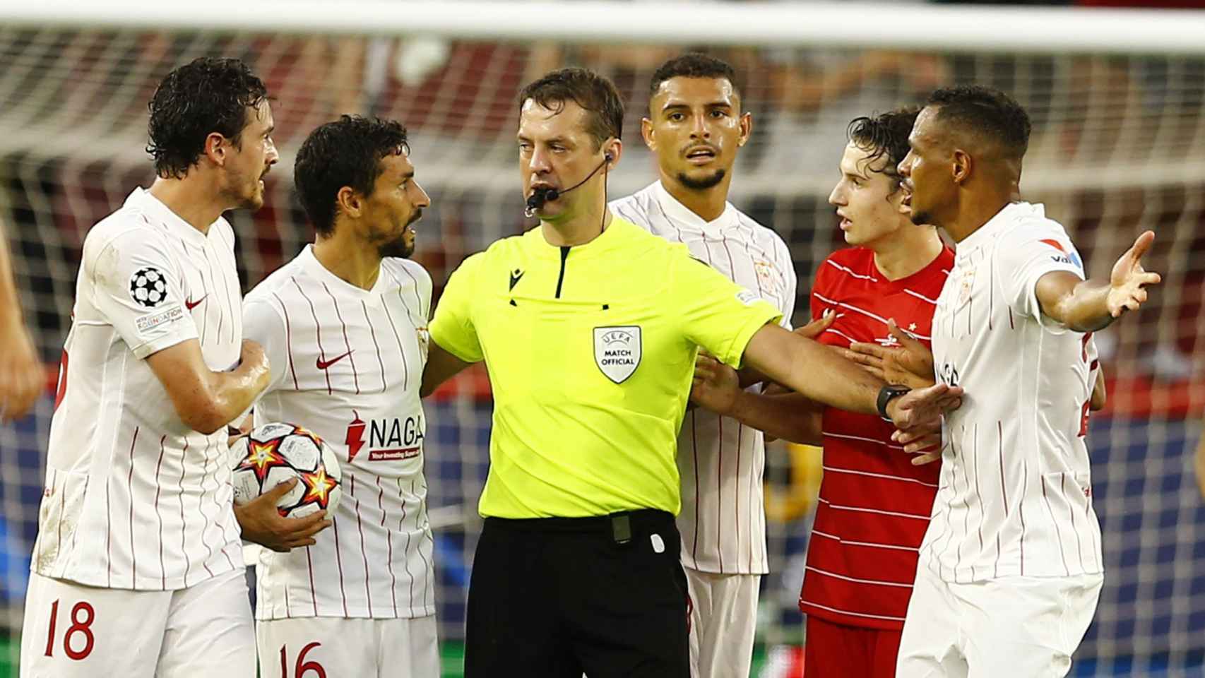 Los jugadores del Sevilla protestan ante el árbitro Aleksei Kulbakov