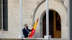 Un ujier se lleva la bandera española de la Galería Gótica del Palau de la Generalitat tras la comparecencia de Pedro Sánchez.