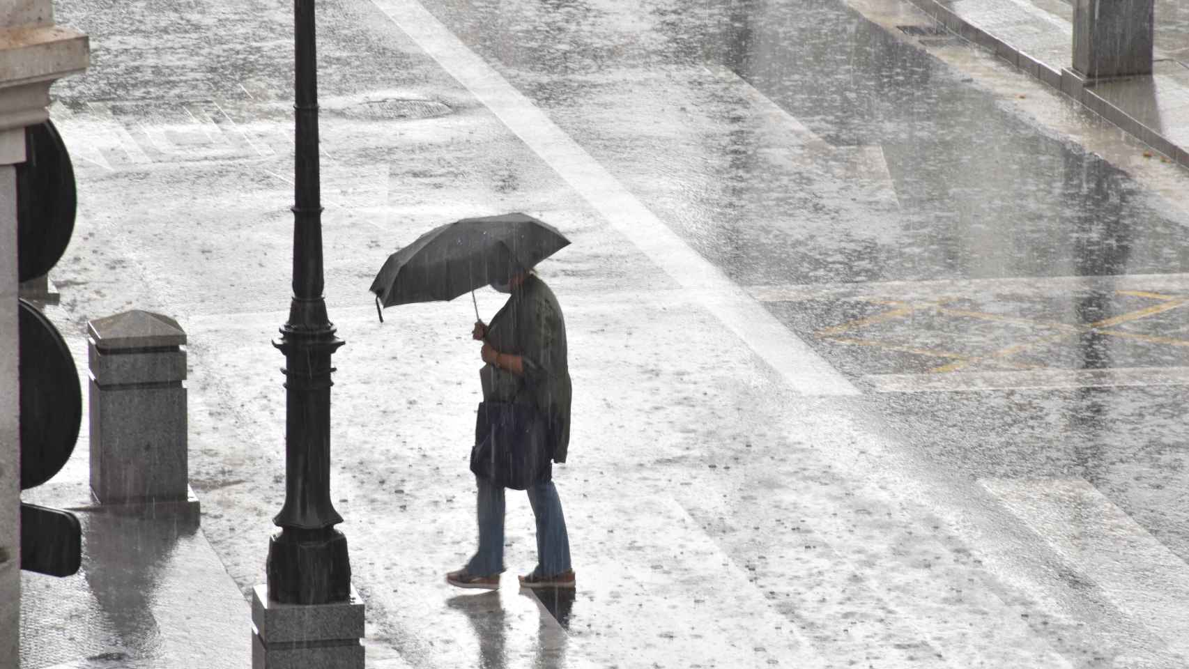 Una mujer se refugia con un paraguas de la intensa lluvia en Valladolid