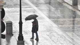 Una mujer se refugia con un paraguas de la intensa lluvia en Valladolid