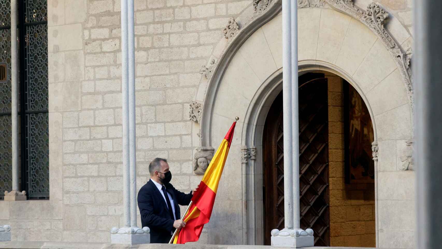 Un ujier recoge la bandera española al término de un acto civil.