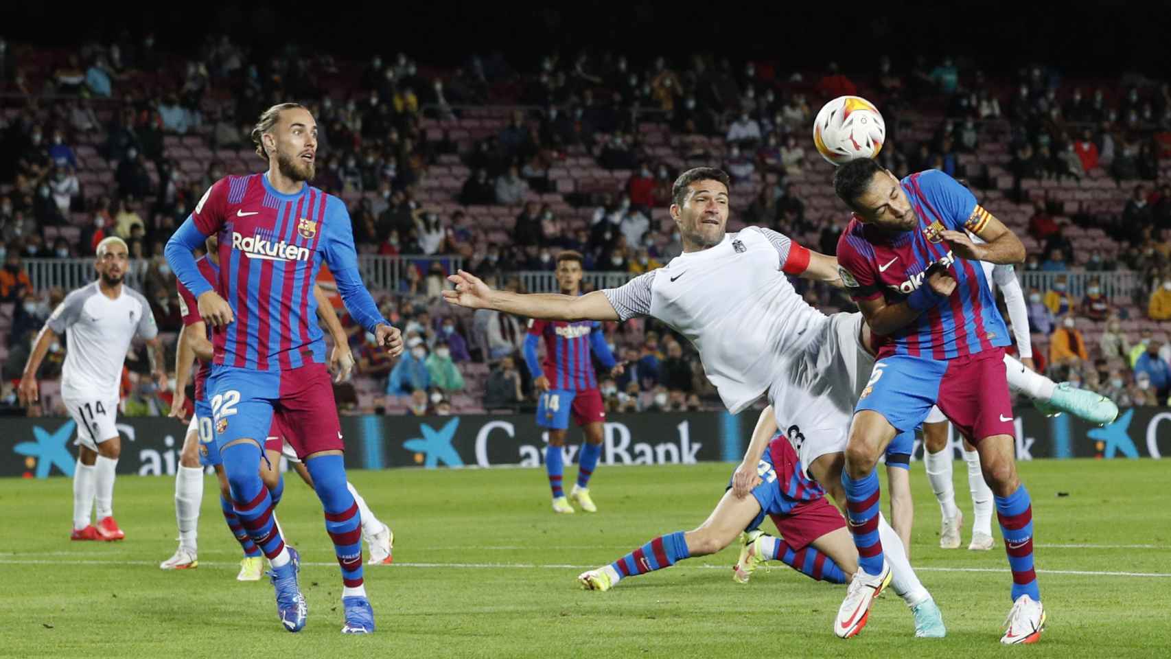 Sergio Busquets saca un balón de cabeza ante Jorge Molina, en el Barcelona - Granada de La Liga 2021/2022