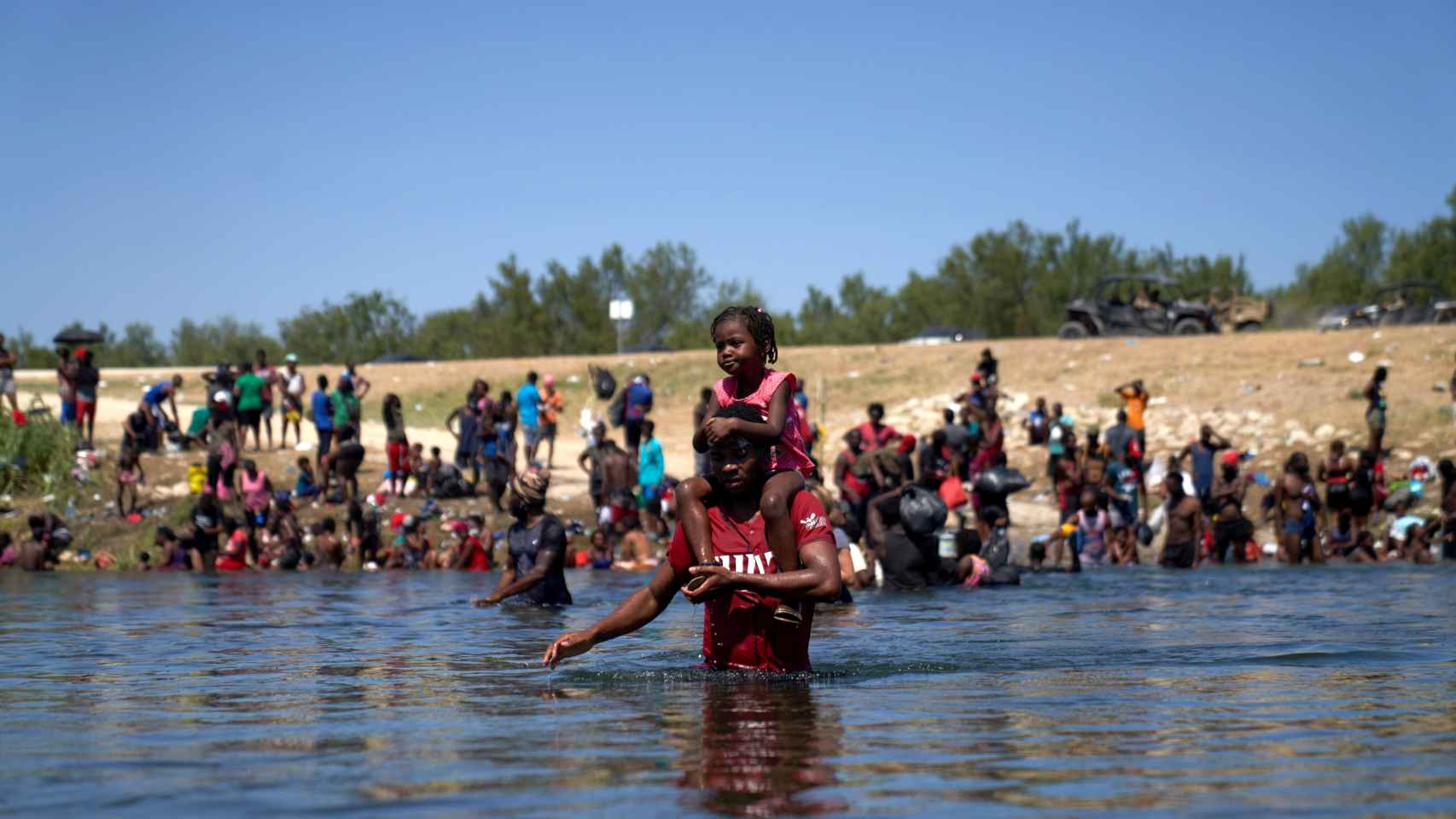 Un emigrante de Haití lleva a un niño a hombros mientras cruza el río Grande de vuelta a México tras ser rechazado en la orilla de Estados Unidos.