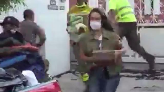 La reportera cargando objetos de la familia afectada.