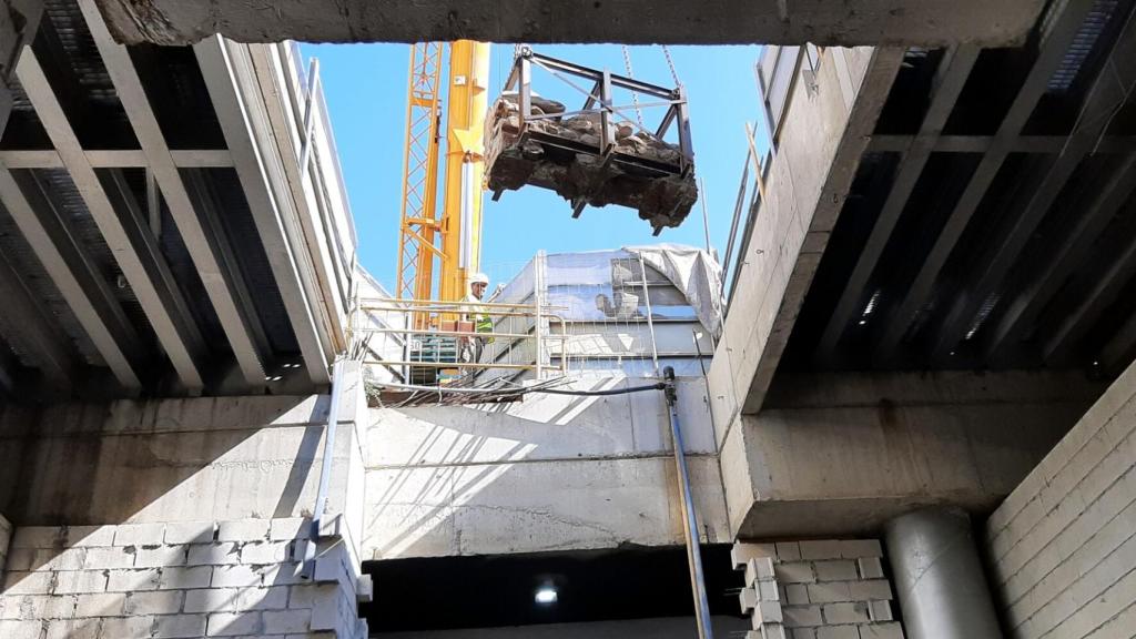 Momento en que una grúa baja uno de los palé con restos del Metro de Málaga.