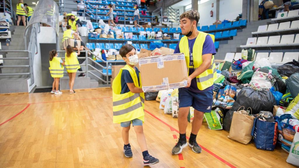 Noah y Fabián ayudan con las donaciones que llegan al pabellón.