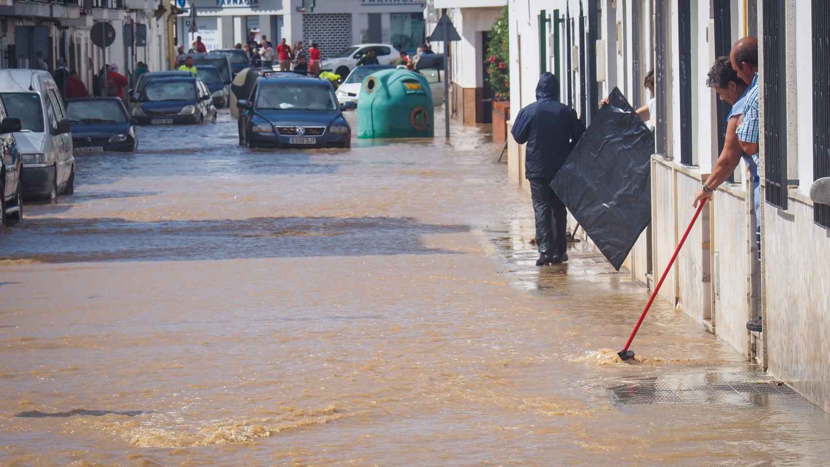 Vecinos de Lepe (Huelva) observando el nivel de agua en una calle inundada.