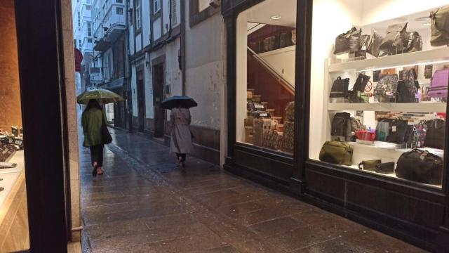 Dos mujeres caminan por la calle Álvaro Cebreiro de A Coruña en un día lluvioso.
