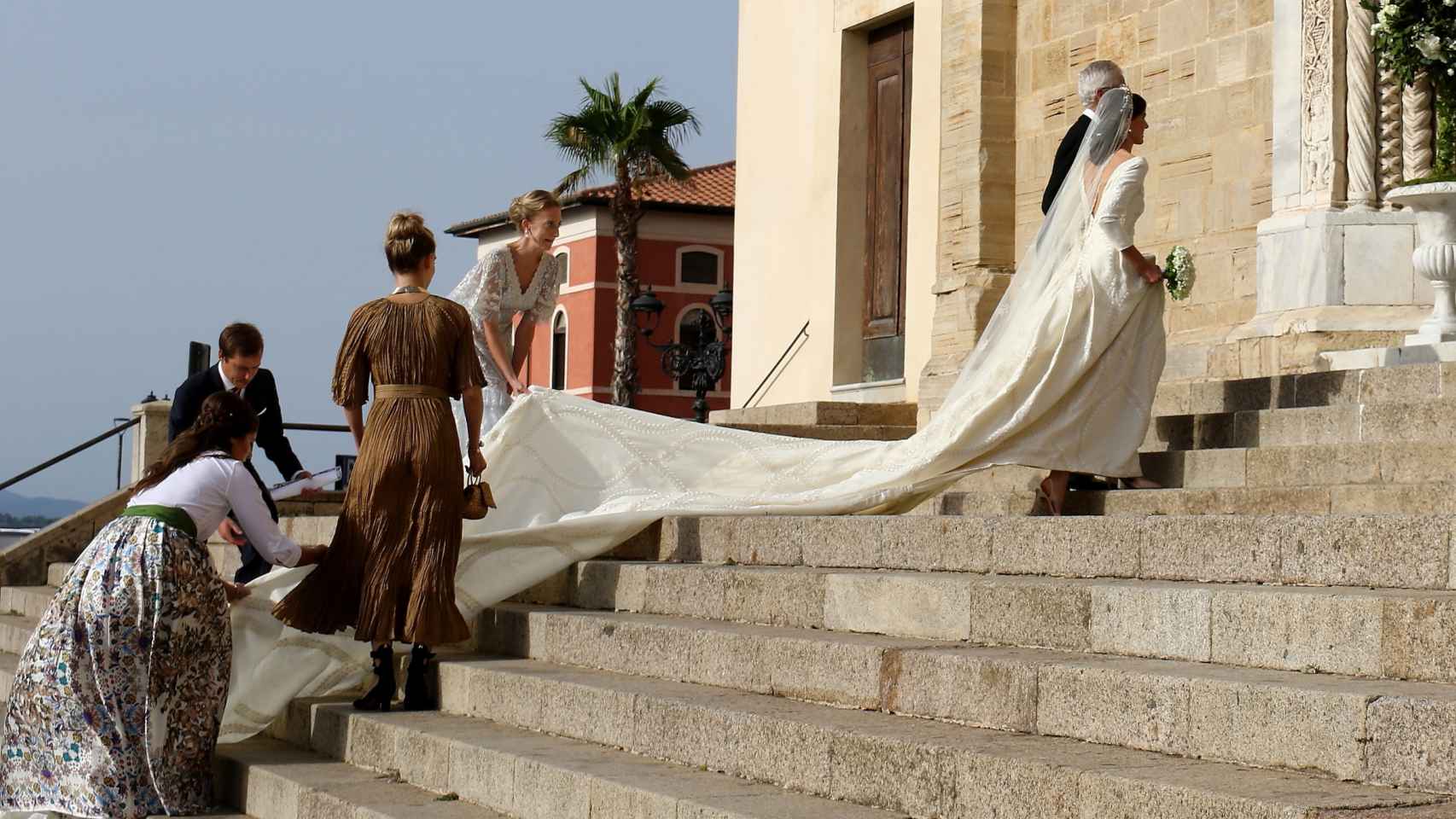 La novia necesitó ayuda con la cola de su traje para subir las escaleras hacia el templo.