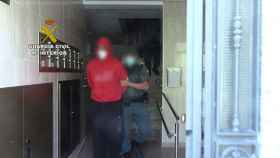 El hombre, en el momento de su detención saliendo de su domicilio esposado por la Guardia Civil..