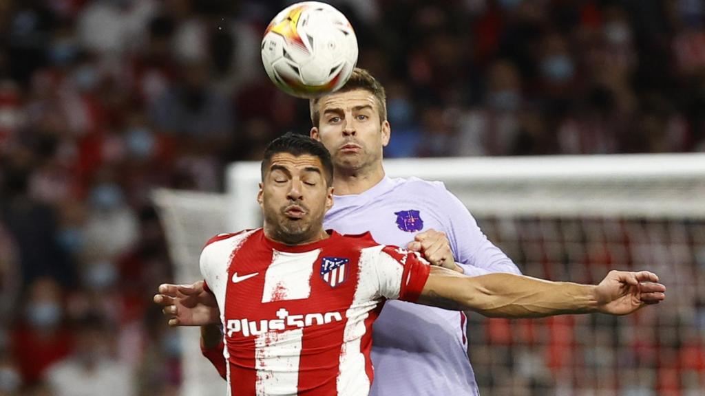 Piqué y Correa pelean un balón de cabeza