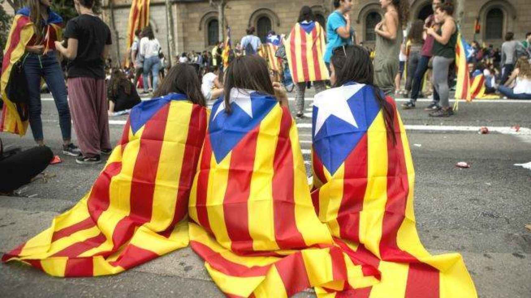 Tres jóvenes con esteladas en la espalda durante una manifestación de la Diada de Cataluña.