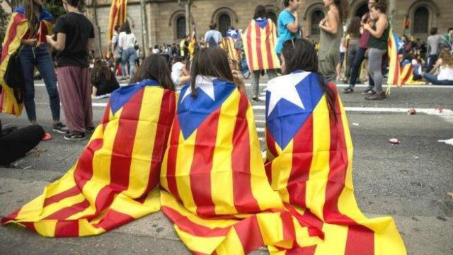 Tres chavales con esteladas en la espalda durante una manifestación de la Diada de Cataluña.