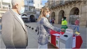 La alcaldesa Lara Méndez depositando unas gafas en un punto de recogida.