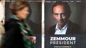 Una mujer pasa delante de un cartel de campaña de Éric Zemmour.