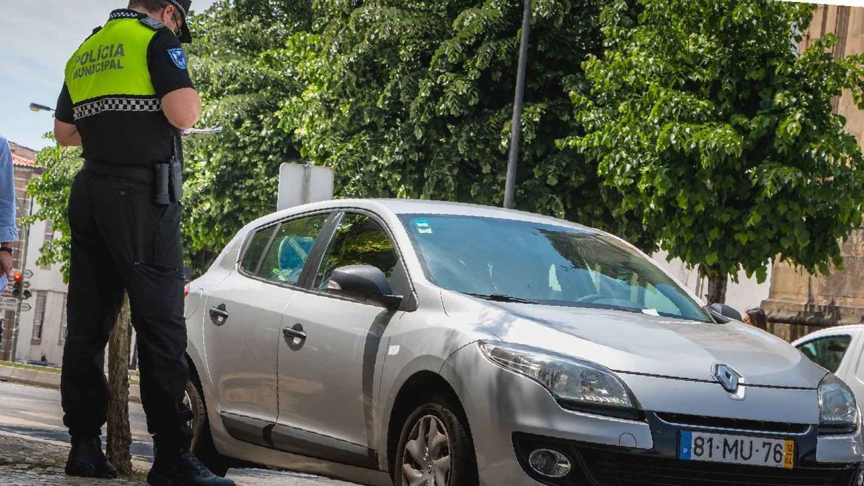 Un policía municipal multa a un coche estacionado.