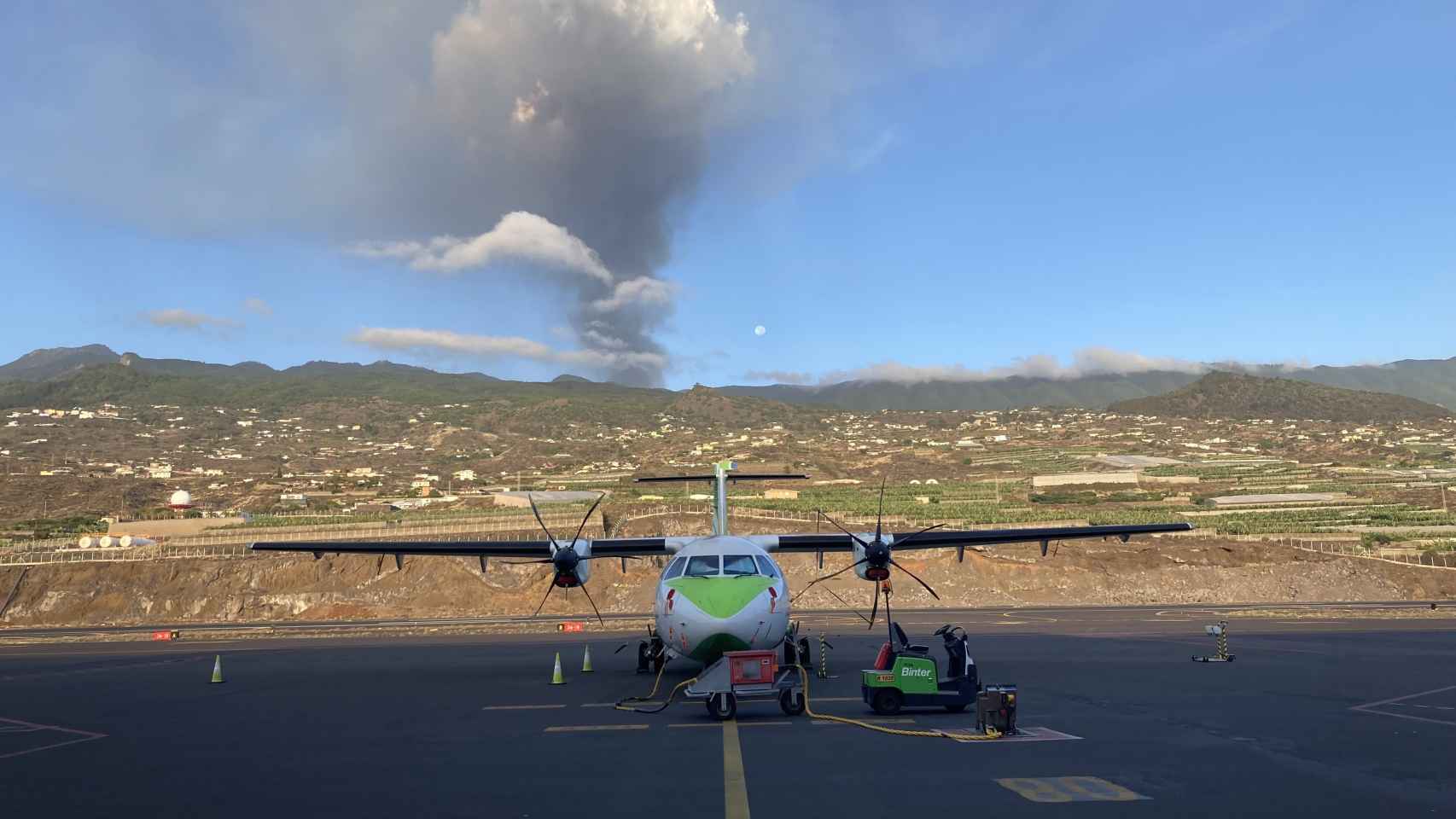 Un avión de Binter en la pista del aeropuerto de La Palma, con el volcán en erupción al fondo.