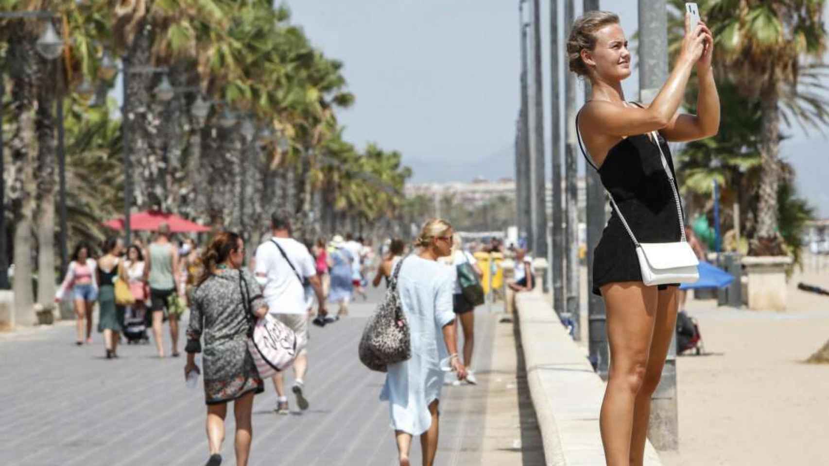 Una turista en la playa utilizando su teléfono móvil.
