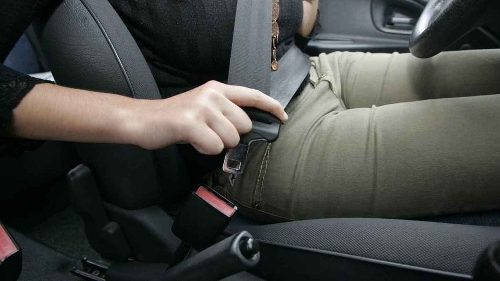 Una conductora se abrocha el cinturón de seguridad en su vehículo.